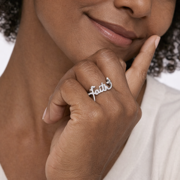 Close-up of a person wearing a silver ring with 'faith' on it, touching their chin.