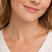 Woman wearing a gold necklace with a neutral background