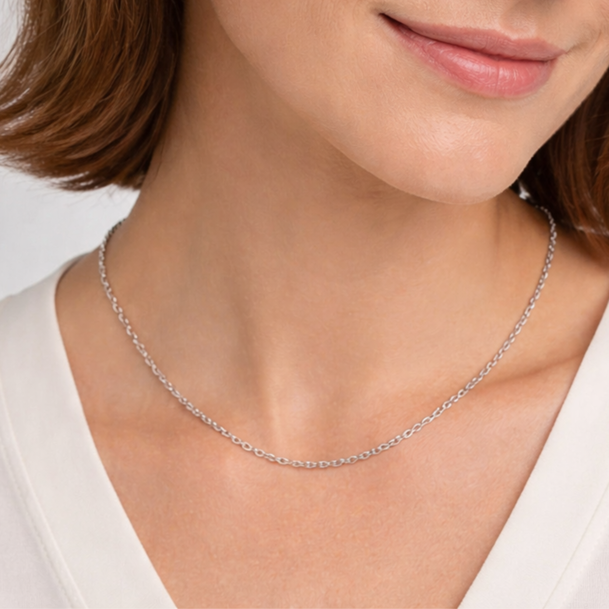 Silver necklace worn by a person against a neutral background