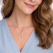 Woman wearing a silver cross necklace with a light blue top.