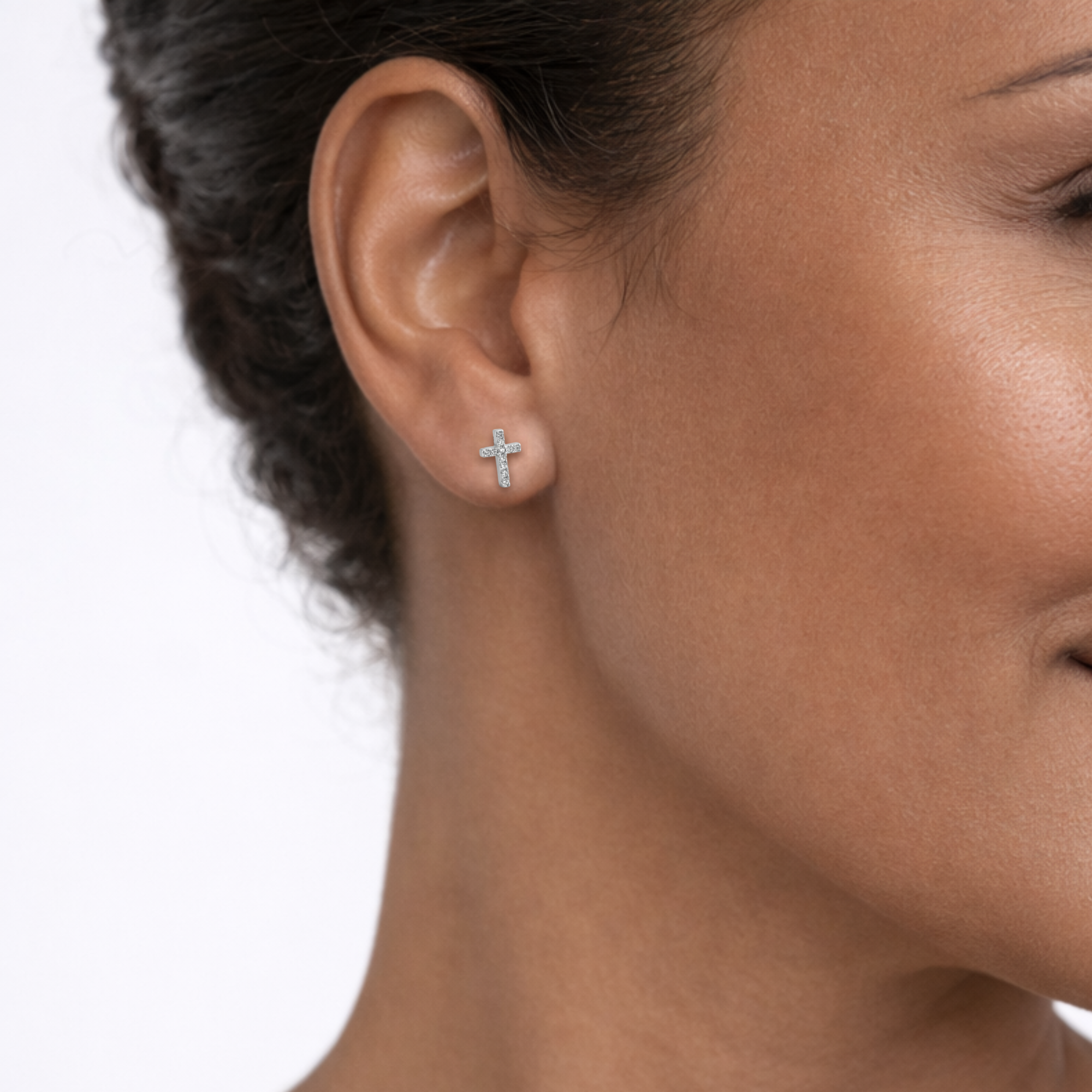 Close-up of a woman wearing a cross-shaped earring on a white background