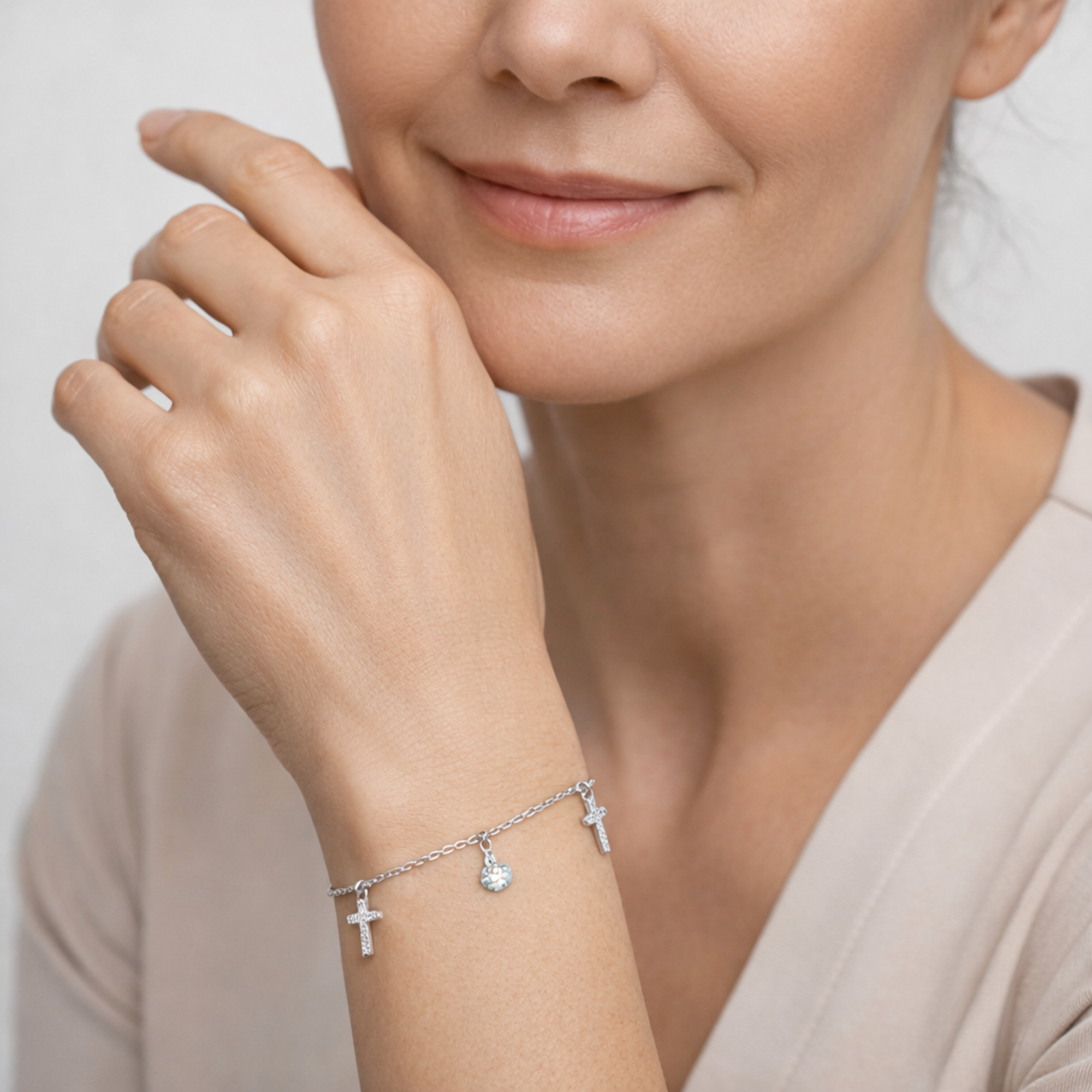 Woman wearing a silver bracelet with charms on a neutral background