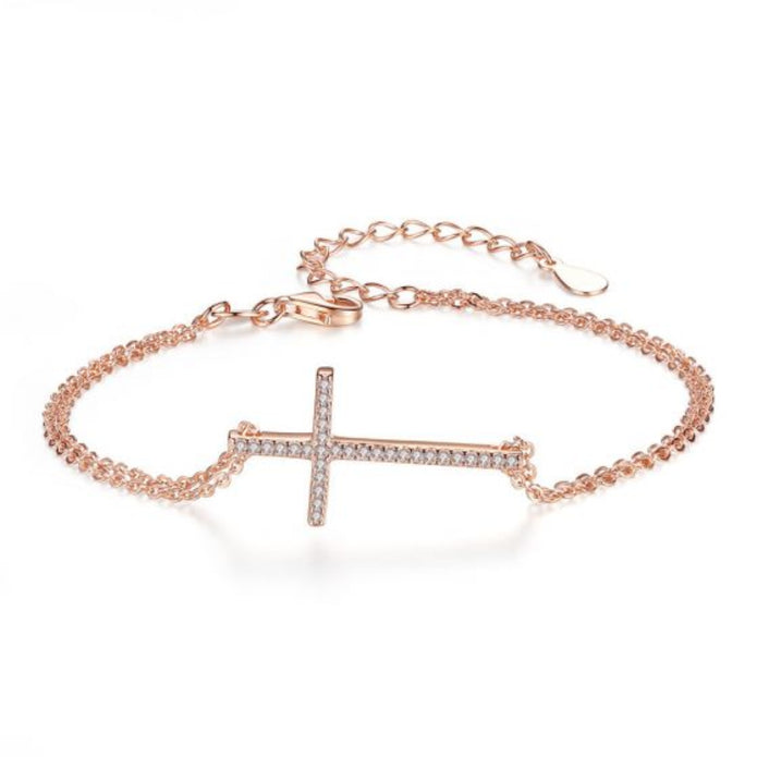 Rose gold bracelet with a diamond-studded cross on a white background