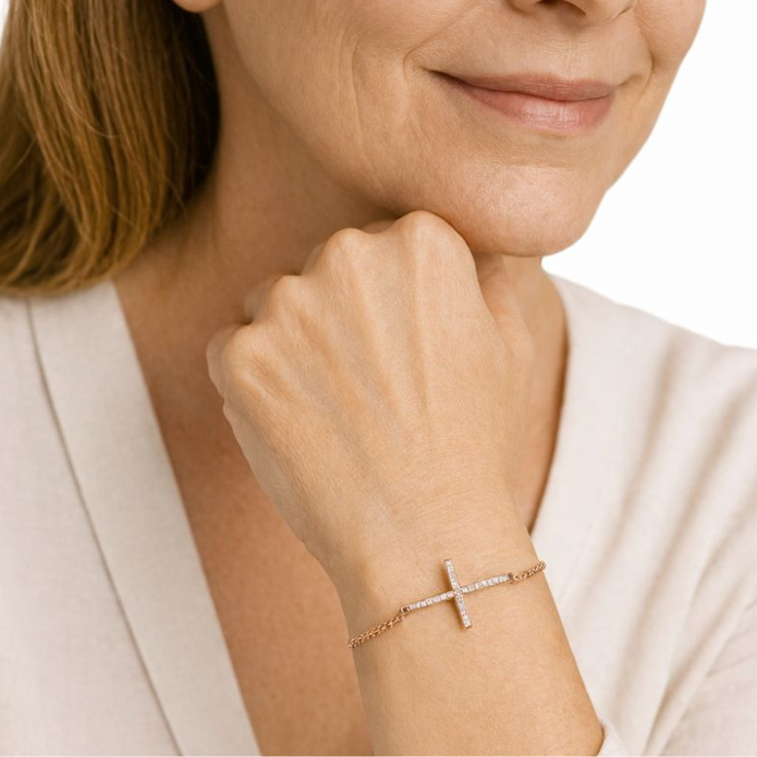 Woman wearing a rose gold bracelet with a cross charm on a white background